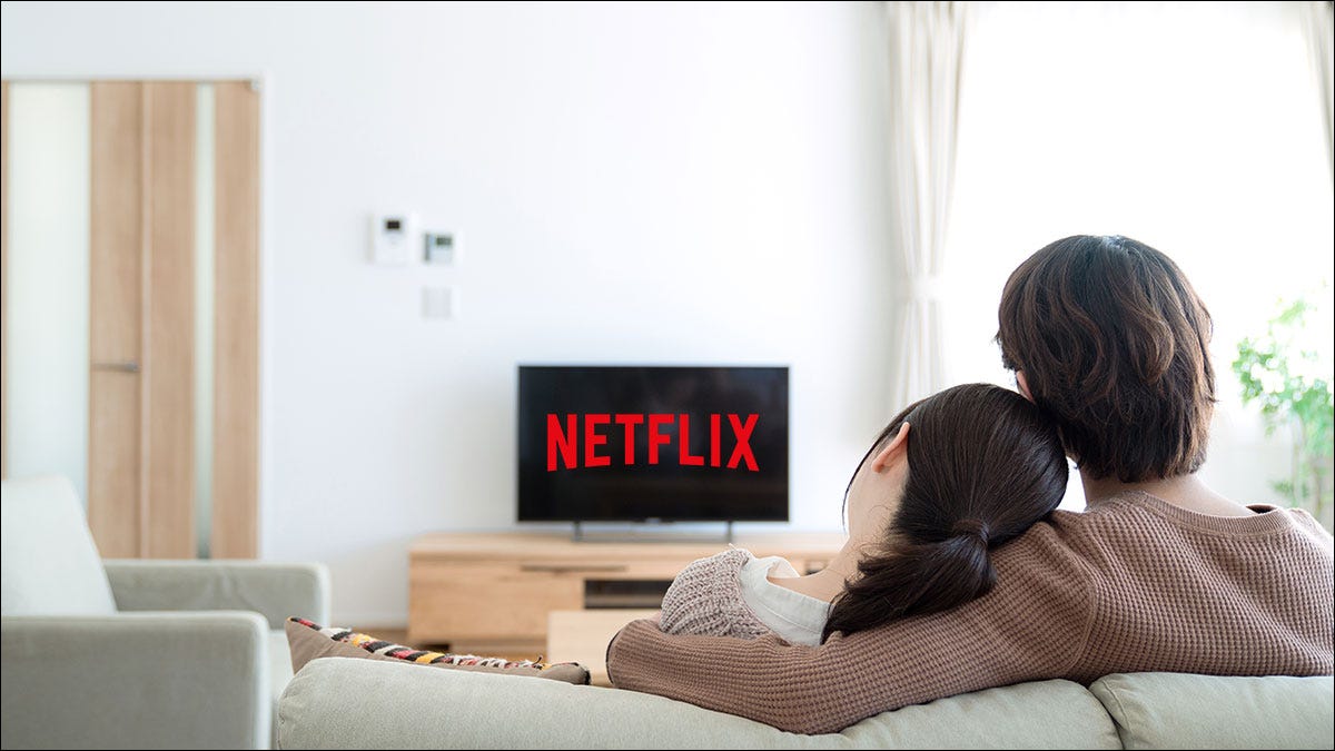 Couple assis sur un canapé regardant Netflix sur un téléviseur