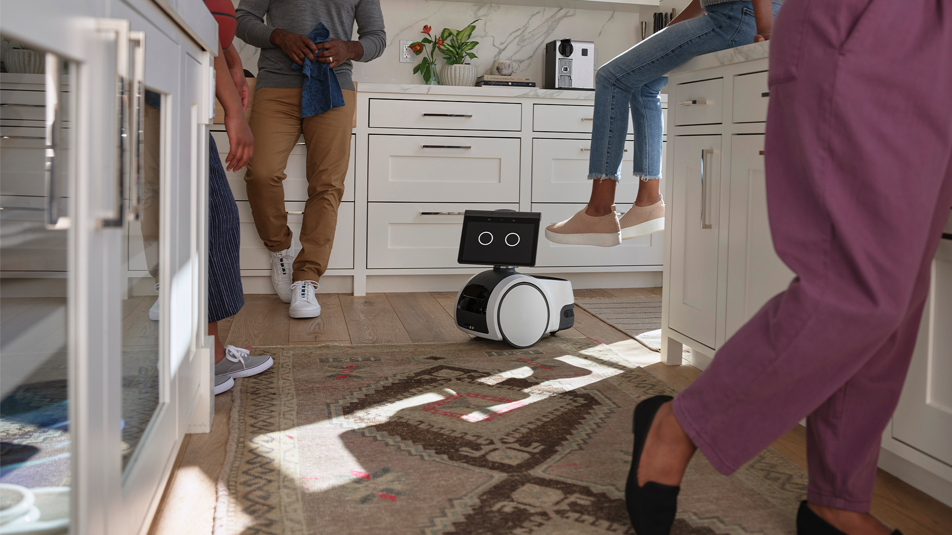 Amazon Astro roulant à travers un groupe de personnes dans une cuisine.