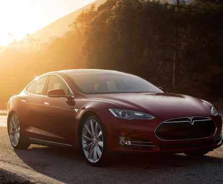 Vue de trois quarts avant d'une Tesla Model S 2015 rouge garée au bord de la route.