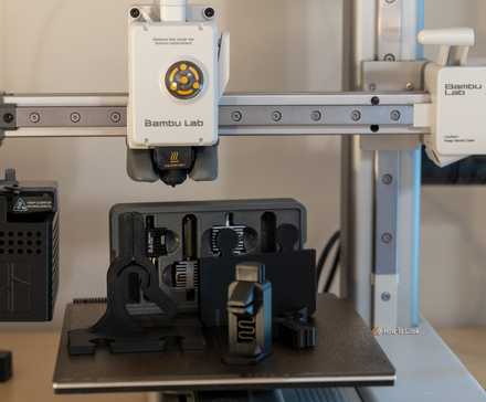 Mini imprimante 3D Bambu Labs A1 avec composants imprimés en 3D posés sur la plaque de construction.