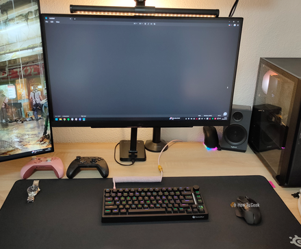 Un bureau d'ordinateur propre avec un PC de jeu, un clavier mécanique, une souris, des contrôleurs et deux moniteurs.