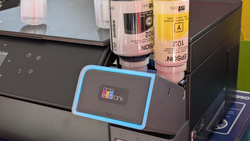 Prise de vue détaillée montrant des bouteilles d'encre noire et jaune remplissant les réservoirs concernés