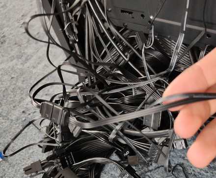 Un désordre de câbles d'ordinateur noirs qui sortent d'un boîtier d'ordinateur.