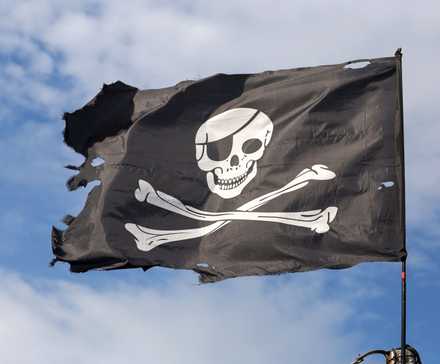 Drapeau pirate Jolly Roger sur fond de ciel bleu..
