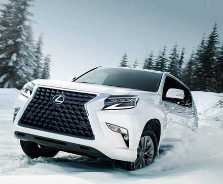 Un Lexus GX 2022 blanc roulant dans la neige dans une zone boisée.