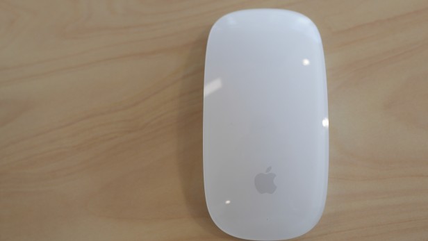 Apple Magic Mouse sur une surface en bois.