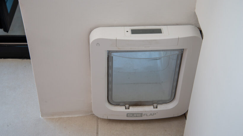 Une Xbox noire et deux manettes PS posées sur une table en bois, vue du dessus